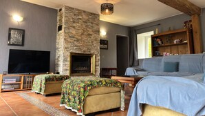 Een woonkamer met een stenen openhaard, een flatscreen televisie en een bank.