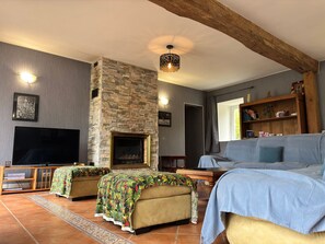 A living room with a stone fireplace, a flat-screen TV, and a sofa.