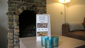 Un panneau affichant le menu, orné d’une illustration de cerf, une cheminée en briques et une table avec trois chandeliers bleus.