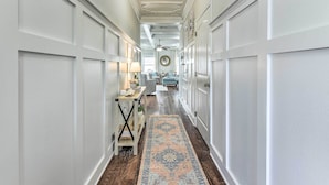A hallway with white paneled walls, a patterned rug, a ceiling fan, and a round mirror on the wall. - Half-Mi to Inlet Beach: Home w/ Grill & Fire Pit (Inlet Beach)