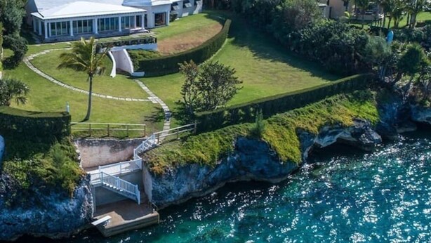 A coastal property with a large house, a private dock, and a well-maintained garden.