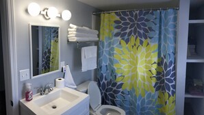 A bathroom with a white sink, mirror, and toilet. There is a shower curtain with a leaf pattern. - Peaceful Pocahontas (Pocahontas)