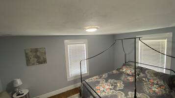 A bedroom with a four-poster bed, a small side table, and a wall-mounted lamp.