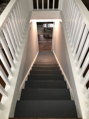 A staircase with white railings and a dark wooden floor leading to a room with a table and chairs. - Peaceful Pocahontas (Pocahontas)