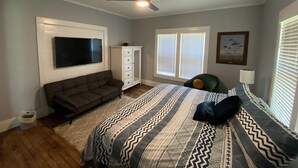 A bedroom with a bed, a ceiling fan, a TV, a cabinet, and a window with blinds. - Peaceful Pocahontas (Pocahontas)