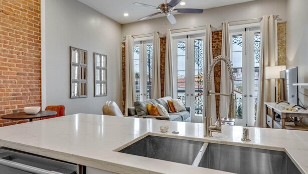 A modern kitchen with a large island, double sink, and a ceiling fan. - Stylish 1BR LGD condo with private balcony on Magazine St. King bed, chef’s kitchen, Wi-Fi, walk to cafés. (New Orleans)