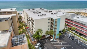 A multi-story hotel with a rooftop pool overlooking a beach. - Sandy Shores 203 2 BR Gulf Front (Madeira Beach)