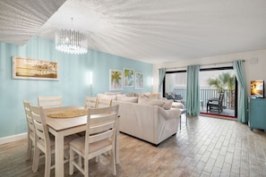 Relax in this stylish living area with a dining table for four, framed artworks, and a sliding glass door to the balcony.