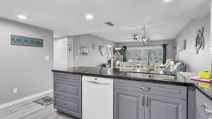 A modern kitchen with grey cabinets, a dishwasher, and a granite countertop. - Sandy Shores 311 Water View 2 BR (Madeira Beach)