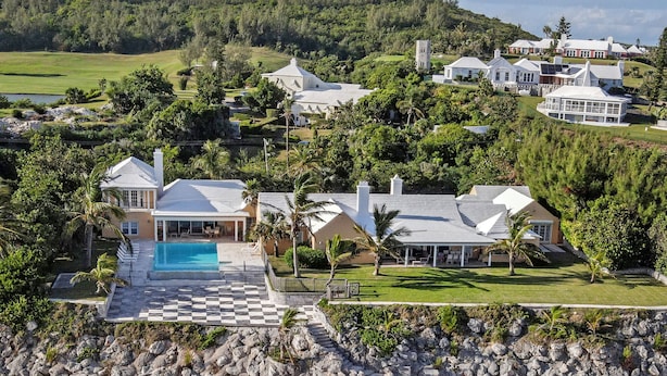Una propiedad costera con piscina, acceso a la playa y varias casas.