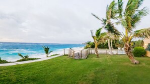 Una propiedad costera con césped, palmeras y vista al océano.
