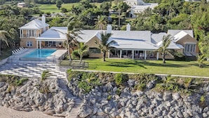 Una propiedad costera con piscina, una casa grande y vistas a la playa.