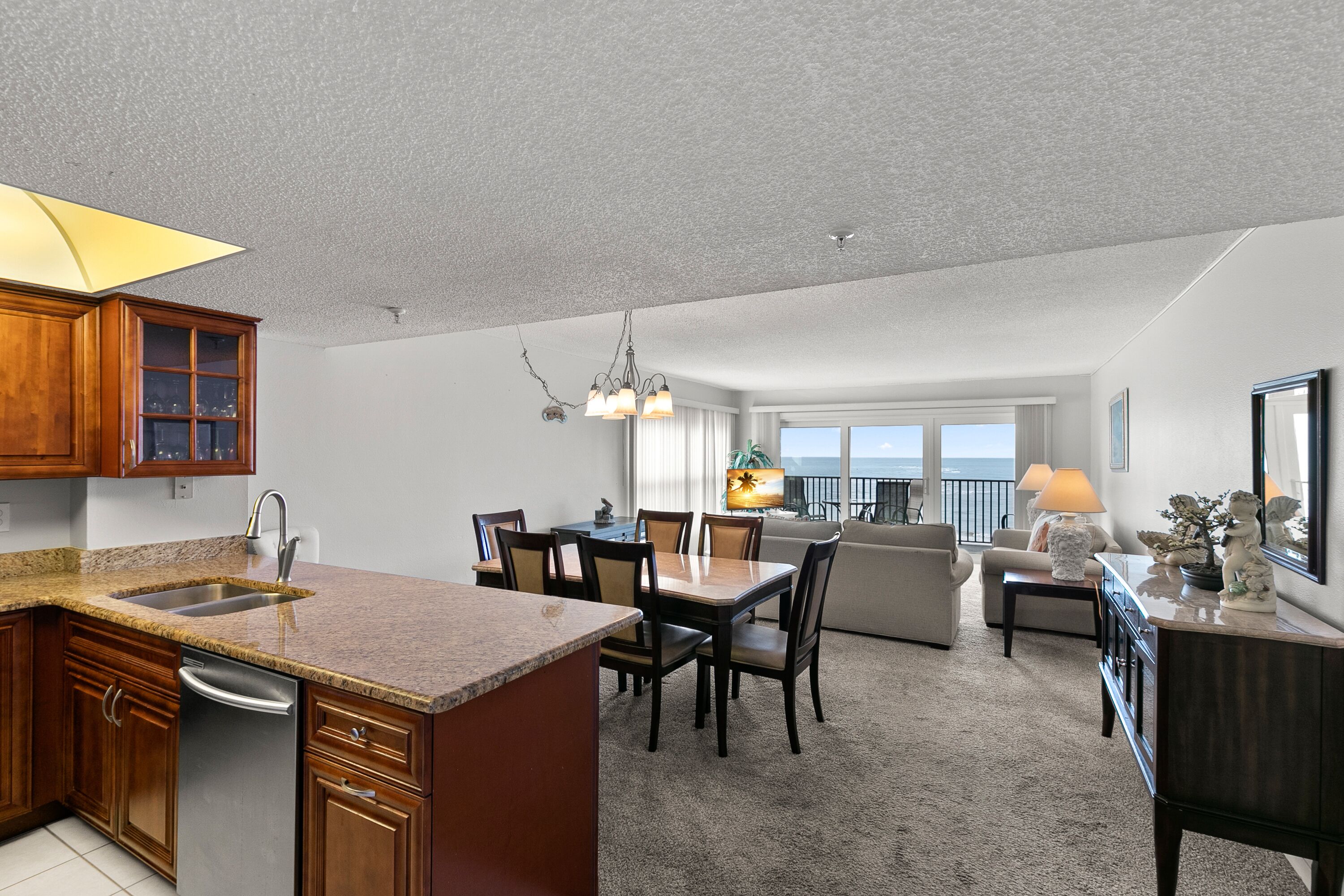 A modern kitchen with granite countertops, wooden cabinets, and a built-in dishwasher.
