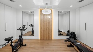 Un gimnasio moderno con suelo de madera, equipamiento de ejercicio y paredes con espejos.