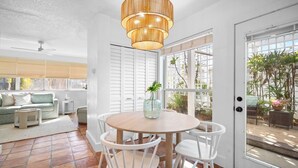 Un comedor con una mesa redonda de madera, sillas blancas y una lámpara colgante.