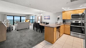 Una cocina moderna con electrodomésticos de acero inoxidable, un comedor con vistas y una sala de estar con sofá y mesa de centro.