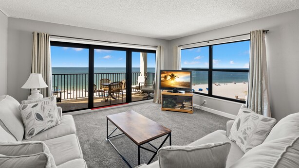 Habitación de hotel con balcón, televisión, sofá y mesa de centro.