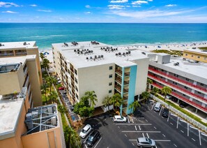 Un edificio de varios pisos con piscina en la azotea y vista a una playa.