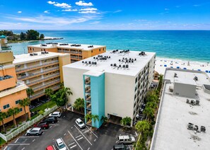 A multi-story hotel with a rooftop pool area overlooking a beach and ocean.