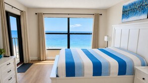 Un dormitorio con una cama grande, vistas al mar y un aparador blanco.