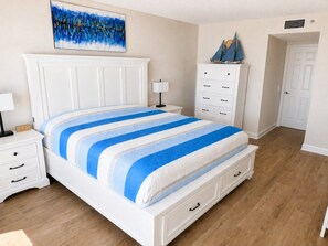 Un dormitorio con cama, mesita de noche, cómoda, un cuadro y una maqueta de un velero.