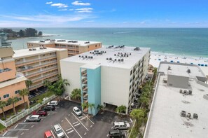Ein Hotel mit mehreren Etagen, einem Parkplatz und Blick auf Strand und Meer.
