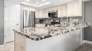 A modern kitchen with white cabinetry, stainless steel appliances, and a granite countertop.