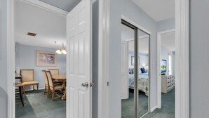 Un pasillo con comedor, un dormitorio con cama y cómoda, y un baño con ducha e inodoro.