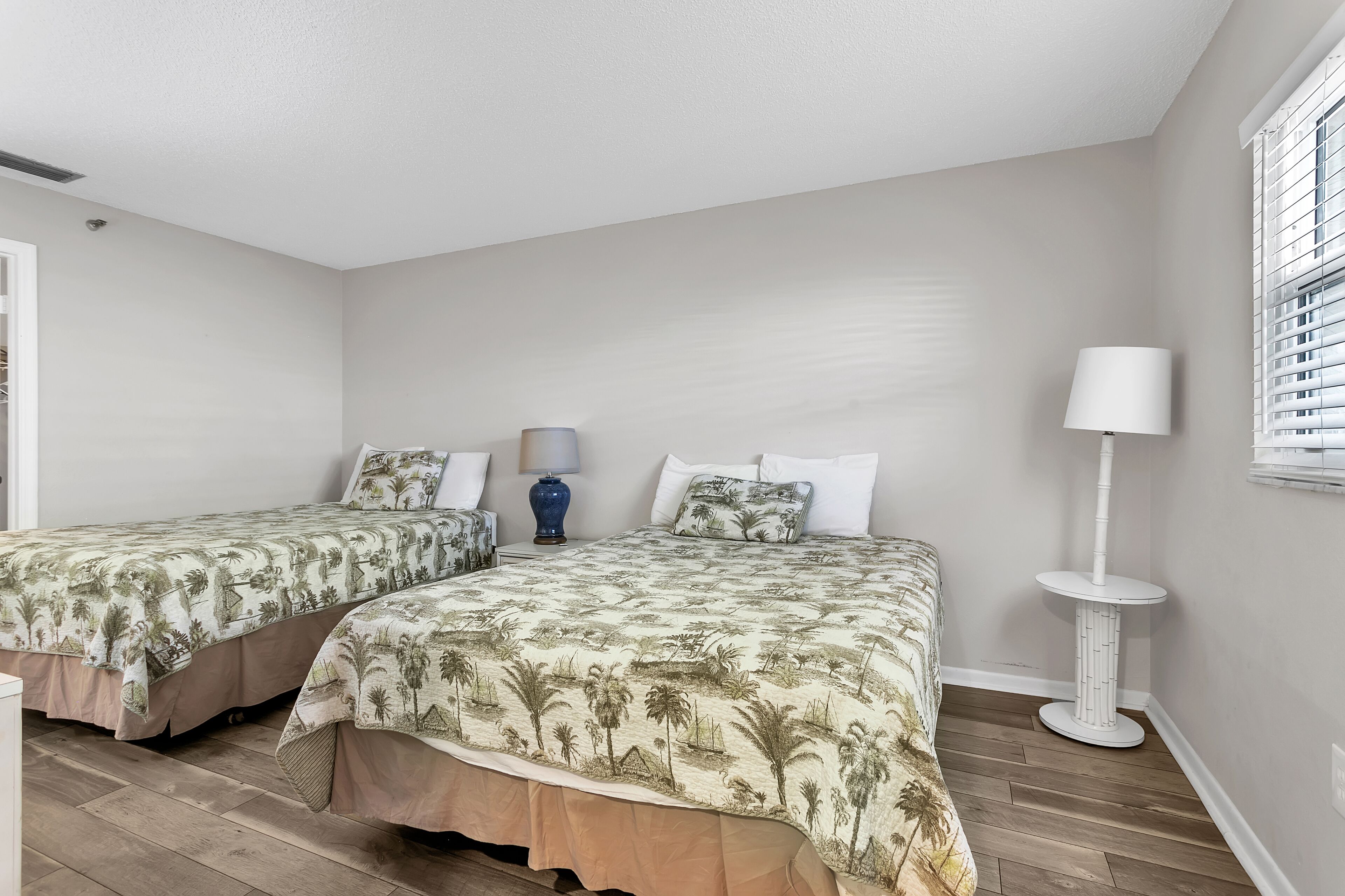 Ein Schlafzimmer mit zwei Betten, jeweils mit passender Blumenbettwäsche, einem Nachttisch mit Lampe und einer Stehlampe.