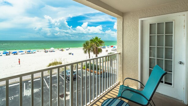 Un balcon donnant sur une plage, une porte et une chaise.