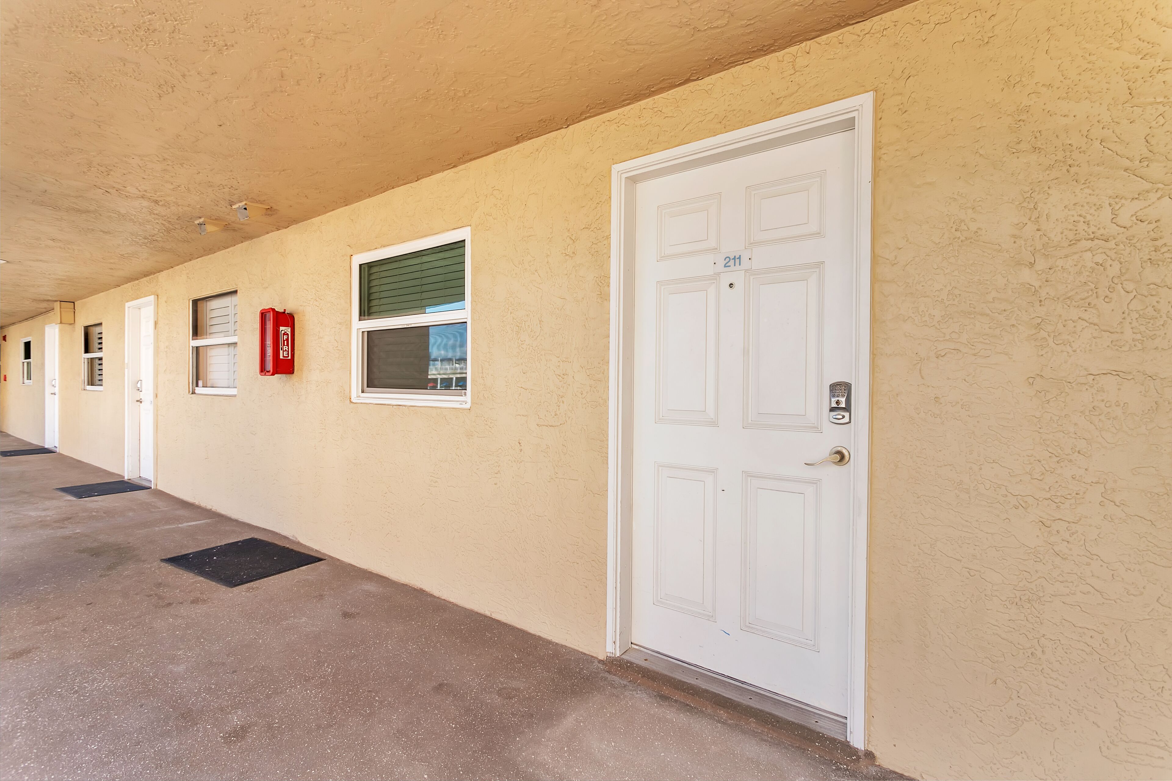 A hallway with doors, windows, and a fire extinguisher.