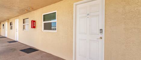 A hallway with doors, windows, and a fire extinguisher.
