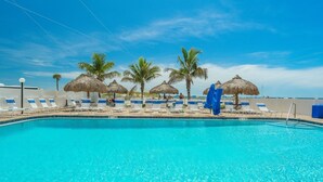 Piscina com espreguiçadeiras e palmeiras.