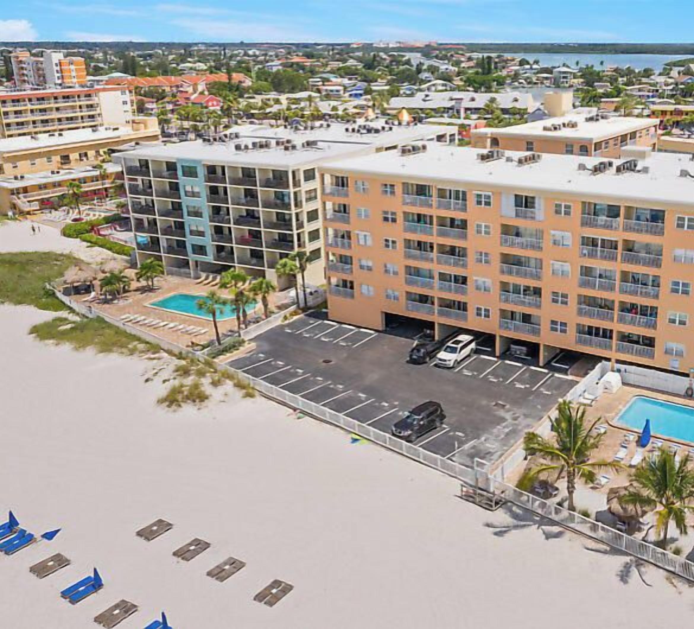 Ein mehrstöckiges Hotel mit Pool, Parkplatz und Zugang zum Strand.
