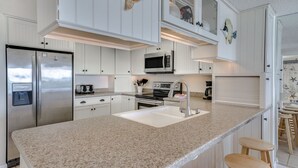 A kitchen with white cabinets, stainless steel appliances, a granite countertop, and a built-in microwave.