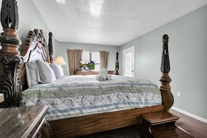 Relax in a spacious bedroom with a large bed, nightstand, and scenic view.