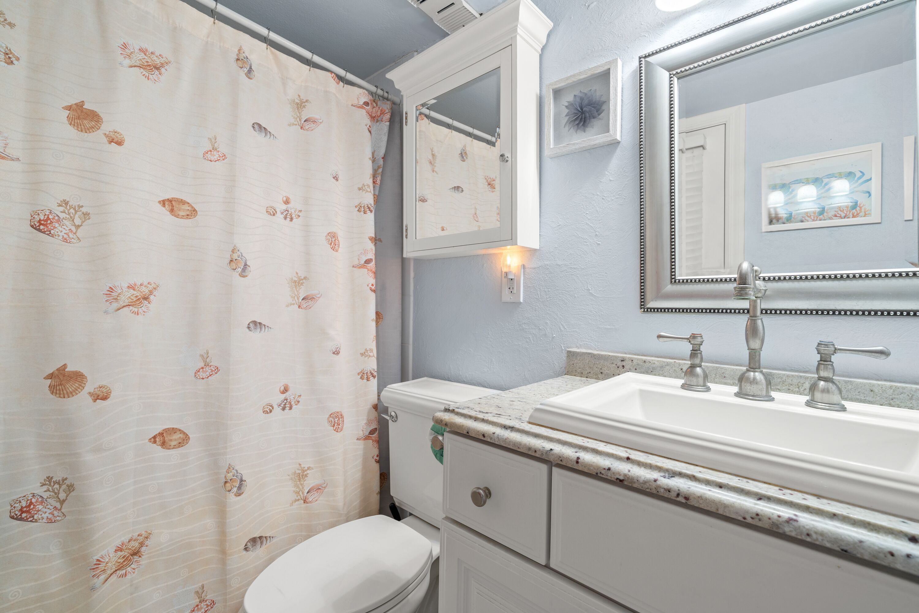 A bathroom with a toilet, sink, and mirror.