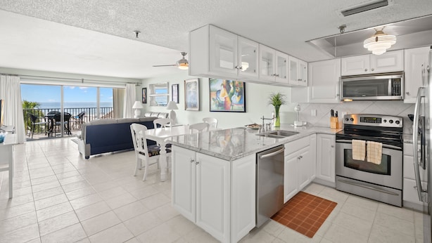 A modern kitchen with white cabinetry, a built-in microwave, and a stainless steel refrigerator. - Get Away In This Well-Appointed Gulf Front Condo (Madeira Beach)