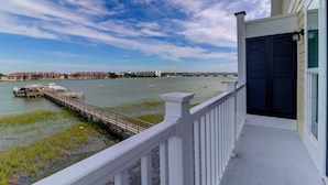 Ein Balkon mit Blick auf einen Fluss, eine Anlegestelle und entfernte Gebäude.