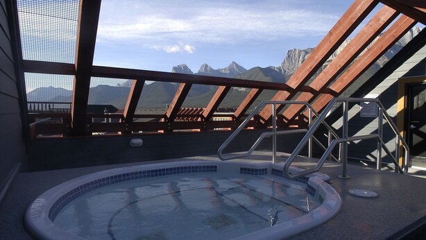 A rooftop hot tub with a view of mountains. - Bear Creek Crossing - Your Cabin In A Condo! (Alberta)