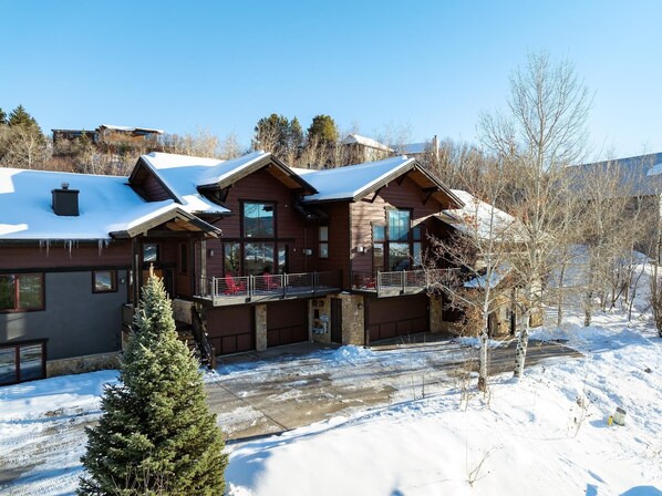 A large log cabin with a balcony and a stone foundation.