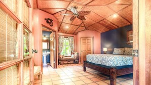 A bedroom with a wooden ceiling, a bed with patterned bedding, a nightstand, and a window with curtains. - House of Paddles, POOL, Ocean close in Keaau, Hawaii, near Hilo (Keaau)