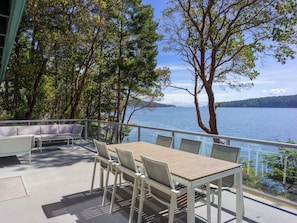 Relax in a serene outdoor space with a view of the lake and distant mountains, surrounded by lush greenery.