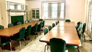 A conference room with a long table, green chairs, a fireplace, and large windows. - Scenic Mountaintop Villa with Free WiFi & Pool (Waynesboro)