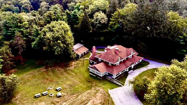 An aerial view of a large, two-story house with a red roof, surrounded by dense trees and a well-maintained lawn. - Scenic Mountaintop Villa with Free WiFi & Pool (Waynesboro)
