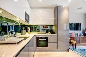 A modern kitchen with a dishwasher, oven, and a built-in TV.