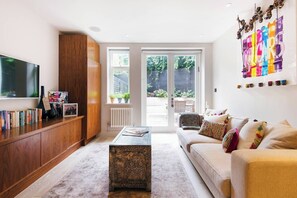 A modern living room with a large TV, wooden cabinet, and a colorful wall art piece.