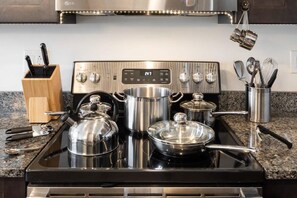 Une cuisine équipée d’une cuisinière en acier inoxydable, de casseroles et d’ustensiles de cuisine.
