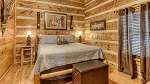 A wooden cabin room with a bed, bedside tables, and a bench. - 4 Bedrooms Near Pigeon Forge-Hot Tub-Pet Friendly-Sleeps 12 (Sevierville)