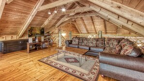 A spacious loft with a high wooden ceiling, a cozy seating area with a sofa and a coffee table, and a wooden reception desk. - 4 Bedrooms Near Pigeon Forge-Hot Tub-Pet Friendly-Sleeps 12 (Sevierville)
